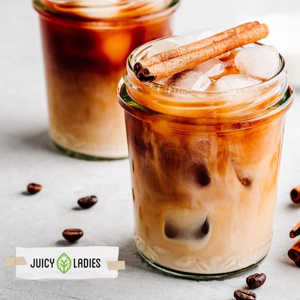 Two iced coffee drinks with cinnamon sticks and coffee beans on a light surface.